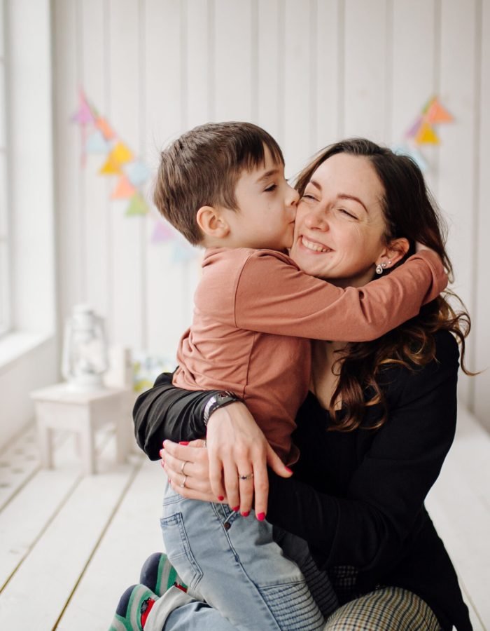 Mother and her son are posing in the studio and wearing casual clothes