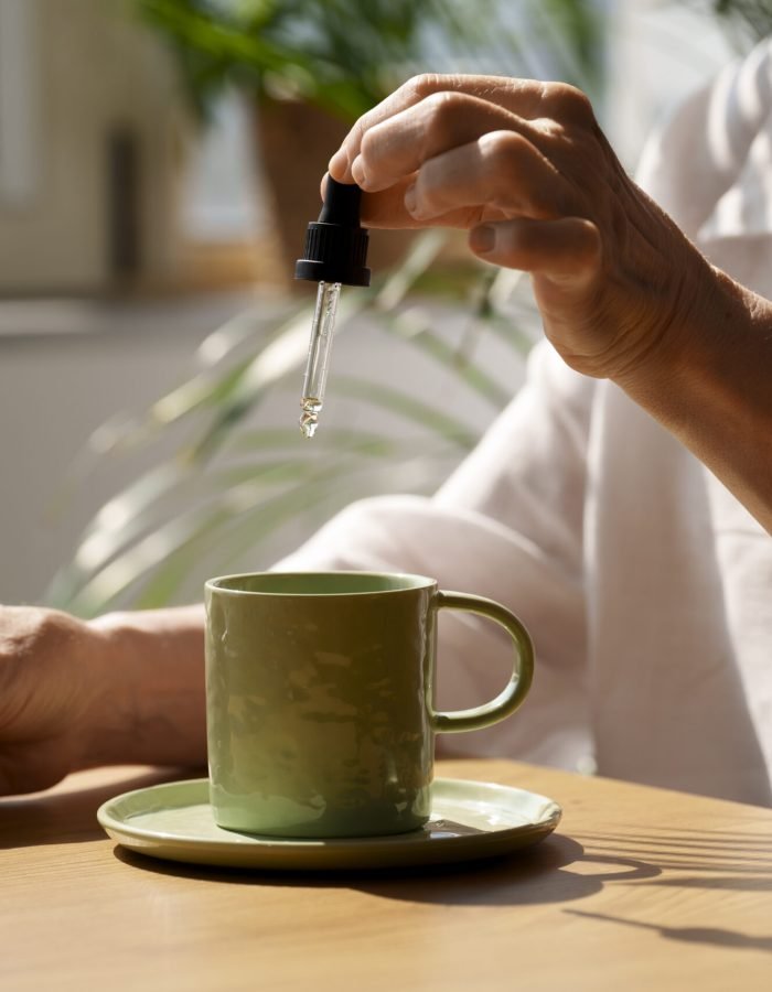 close-up-woman-putting-cbd-oil-drink