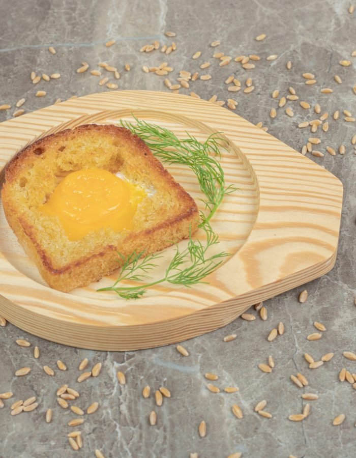 Fried egg inside toast bread slice on wooden plate. High quality photo